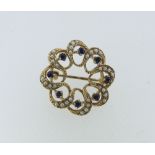 A small 9ct yellow gold open circular Brooch, set with seed pearls and sapphires, 1in (2.5cm)