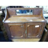 An Edwardian oak Hanging Cabinet, with a central rectangular mirror, upon two doors enclosing a