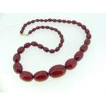 A graduated Cherry Amber Bead Necklace, formed of forty five oval beads, gilt metal barrel snap,