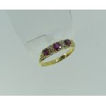 A graduated five stone ruby and diamond Ring, the three oval facetted rubies with two vertical