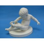 A Gustafsberg parian porcelain figure of a Child, seated and pulling off a sock, impressed maker's