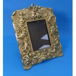 A Rococo-style gilt-metal easel Photo Frame, moulded in relief with cherubs and putti, 11¾in x