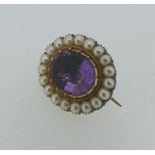 An antique closed back oval Brooch, the centre set with an oval facetted purple stone, with a