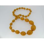 A butterscotch Amber Necklace, formed of thirty graduating oval beads, one forming screw clasp,