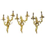 A set of three early 20th Century Louis XV style cast gilt metal twin branch wall sconces