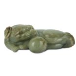 A CHINESE PALE CELADON CARVING OF A LION DOG WITH A BALL.