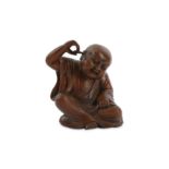 A CHINESE WOOD CARVING OF A BOY CLEANING HIS EAR.