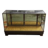 AN EARLY 20TH CENTURY BRASS MOUNTED GLAZED TEAK SHOP / HABERDASHERY CABINET