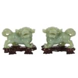 A pair of modern Chinese carved pale green jadeite lion dogs