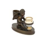 A 19th century patinated bronze encrier in the form of a seated winged cherub