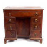 A George III mahogany kneehole desk fitted drawers around a recess with cupboard,