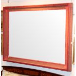 A large wall mirror, the rectangular plate in a concave frame with pink fabric covering,
