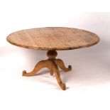 A circular pitch pine table on a turned column and tripod support,
