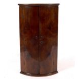 An 18th Century walnut bowfront corner cupboard,