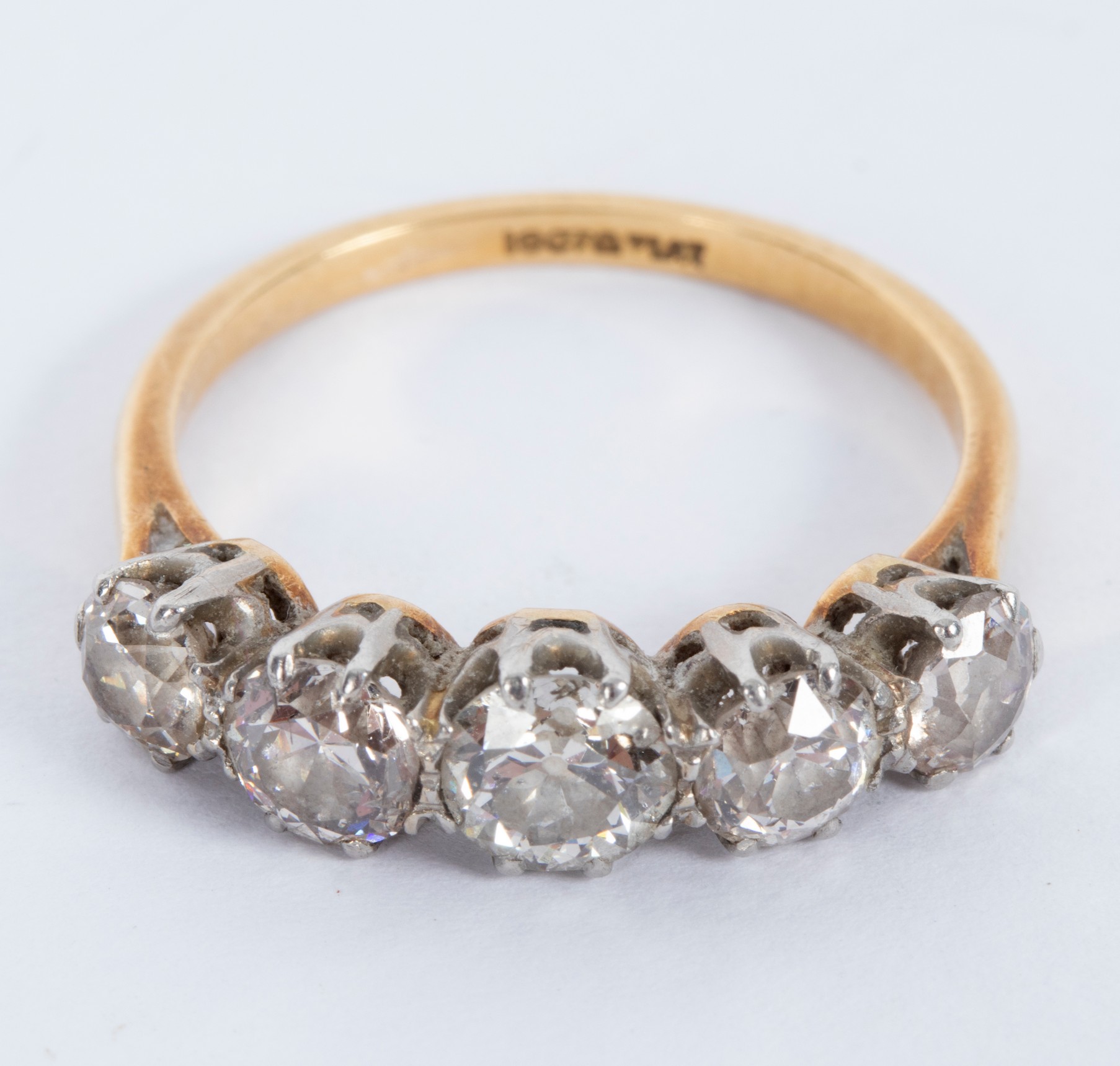 A diamond five-stone ring in a scroll setting, set in platinum to an 18ct yellow gold shank,