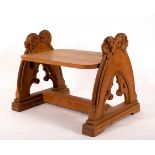 A 19th Century oak stool of Gothic design with arched ends, each with berry and foliate finials,