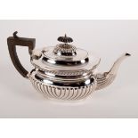 A silver teapot, LF Birmingham 1918, half-ribbed with ebonised handle,