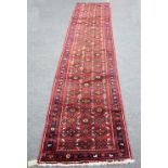 A Hamadan runner with geometric design to a deep red field within a multiple border,