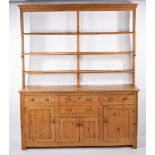 A pine dresser, the open rack above a base fitted an arrangement of drawers and cupboards,