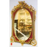 An Empire style gilt framed mirror with crossed torches to the crest, set with an oval mirror plate,