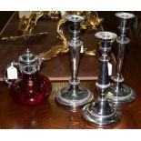 Three plated candlesticks and a ruby tinted glass claret jug with plated mounts
