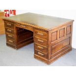 An oak pedestal desk fitted nine drawers around a kneehole, panelled sides,