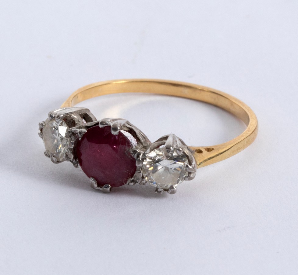 A ruby and diamond three-stone ring, claw set in white metal to a yellow metal shank,