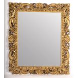 A carved and gilded frame with pierced decoration of leaf scrolls and shells, fitted a mirror plate,