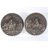 A silvered pair of cast metal roundels depicting putti on a goat and putti on a hound, 32.
