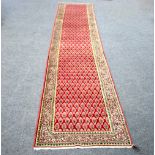An Araak runner with repeating motif to a tomato red field within a geometric border,