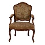 A carved beechwood framed fauteuil with needlework panel back,
