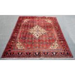 A Hamadan rug with central geometric medallion to a brick red field with ivory spandrels within a