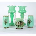 A pair of Victorian opaque green glass vases each decorated with lily of the valley and set on