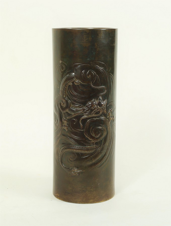 A Japanese Meiji period cylindrical bronze vase decorated a dragon in swirling clouds,