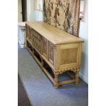 A bleached oak sideboard, the three drawer front flanked by two-door cupboards and reeded pilasters,