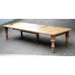 A bleached oak extending dining table with moulded border, raised on five carved acanthus legs,