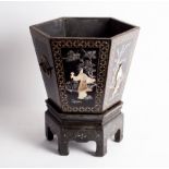 A Japanese black lacquer jardinière on a stand of tapered hexagonal form and decorated in raised