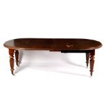 A Victorian mahogany extending dining table with half round ends, raised on four round reeded legs,