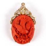 A carved coral pendant of oval shape depicting a bird on a branch, set in 14k yellow gold,