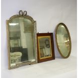 A gilt framed wall mirror with ribbon cresting above an arched bevelled plate,