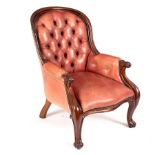 A Victorian button back easy chair upholstered in faded red leather,