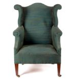 An upholstered wing back armchair with shaped back and scroll wings,