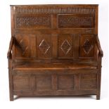 A Jacobean oak settle, the panel back with later carved decoration above a box seat, 129.