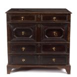 A 17th Century style oak chest of four long drawers with geometric mouldings to the fronts,