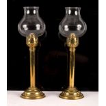A pair of brass spring loaded candlesticks of column form with later bulbous glass shades,