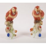 A pair of Herend models of red parrots perched on fruit encrusted tree stumps,