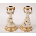 A pair of glazed and biscuit porcelain figural candlesticks,