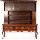 A 19th Century oak dresser, the rack fitted three shelves and flanked by two cupboards,