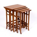 An Arts & Crafts style nest of four oak tables with slatted side supports,