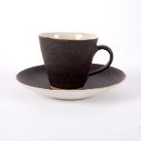 Lucie Rie (1902-1995), a teacup and saucer, in manganese glaze with cream interior, impressed mark,